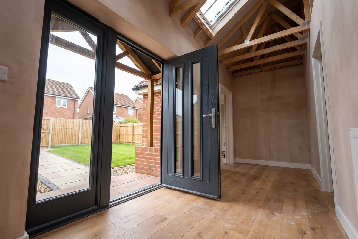 Anthracite door with two tall glazed panels standing open in a timber-framed extension