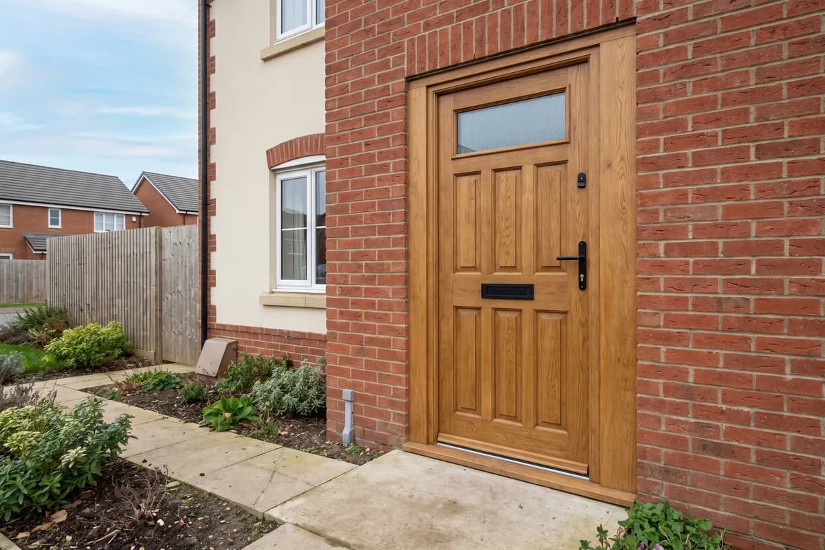 Oak-effect panelled front door with a glazed top panel set in a red brick wall