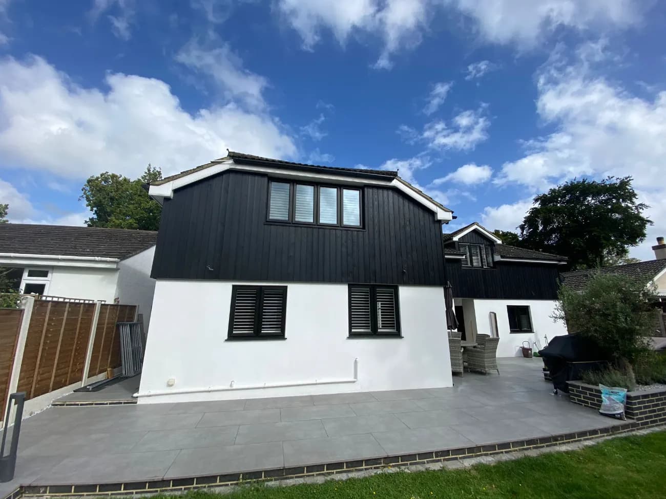 House exterior finished with black vertical timber cladding above white render walls