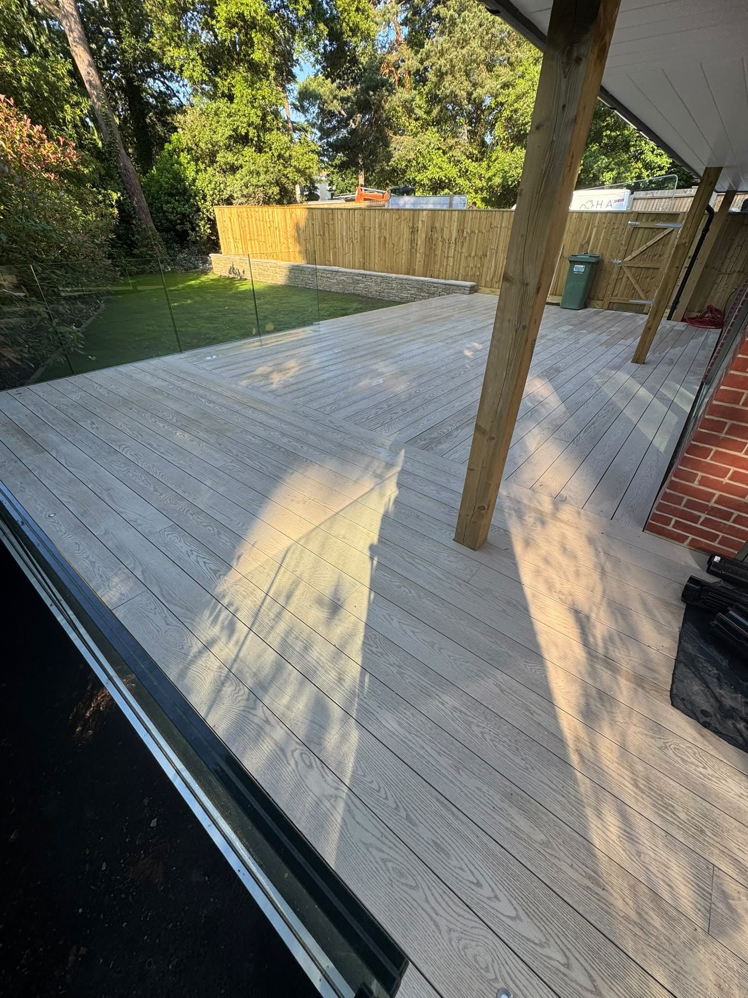 Composite decking with frameless glass balustrade under a timber-post veranda