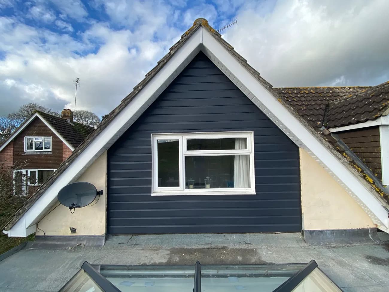Dark grey timber cladding finished on a house gable end with white fascias