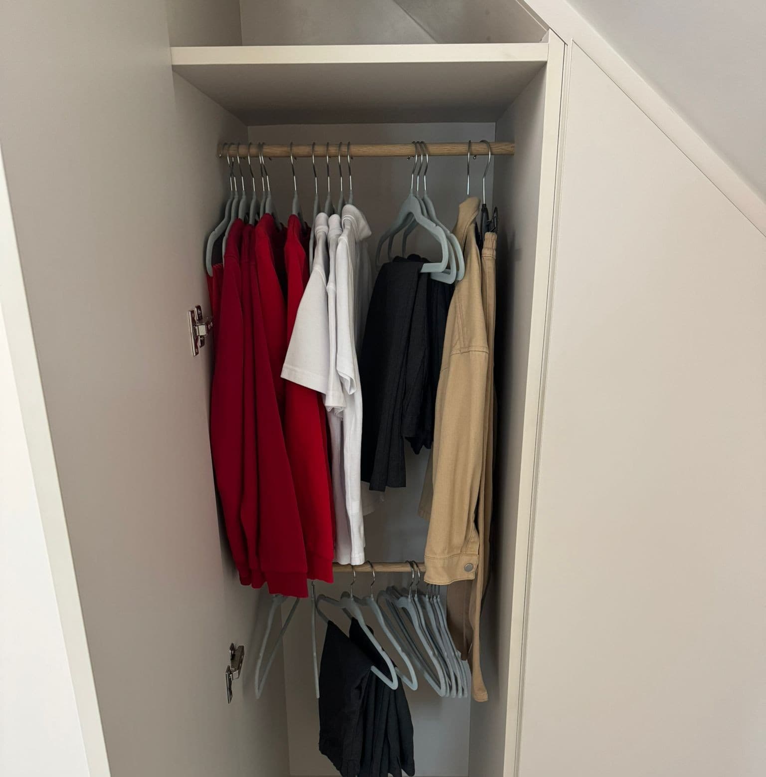 Fitted wardrobe with sloped ceiling, double hanging rails and clothes