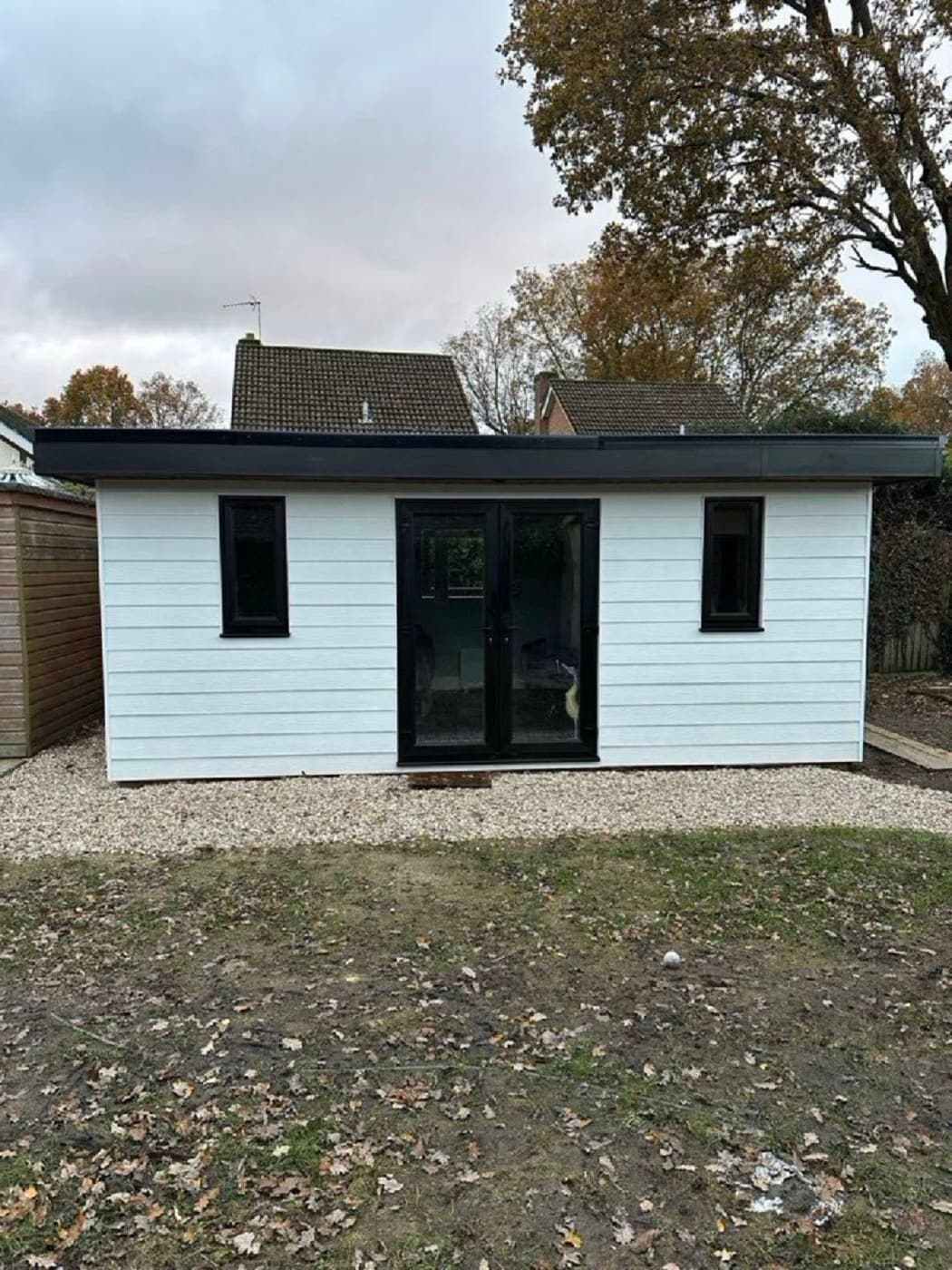 Finished white-clad garden office with flat black roof and black-framed double doors