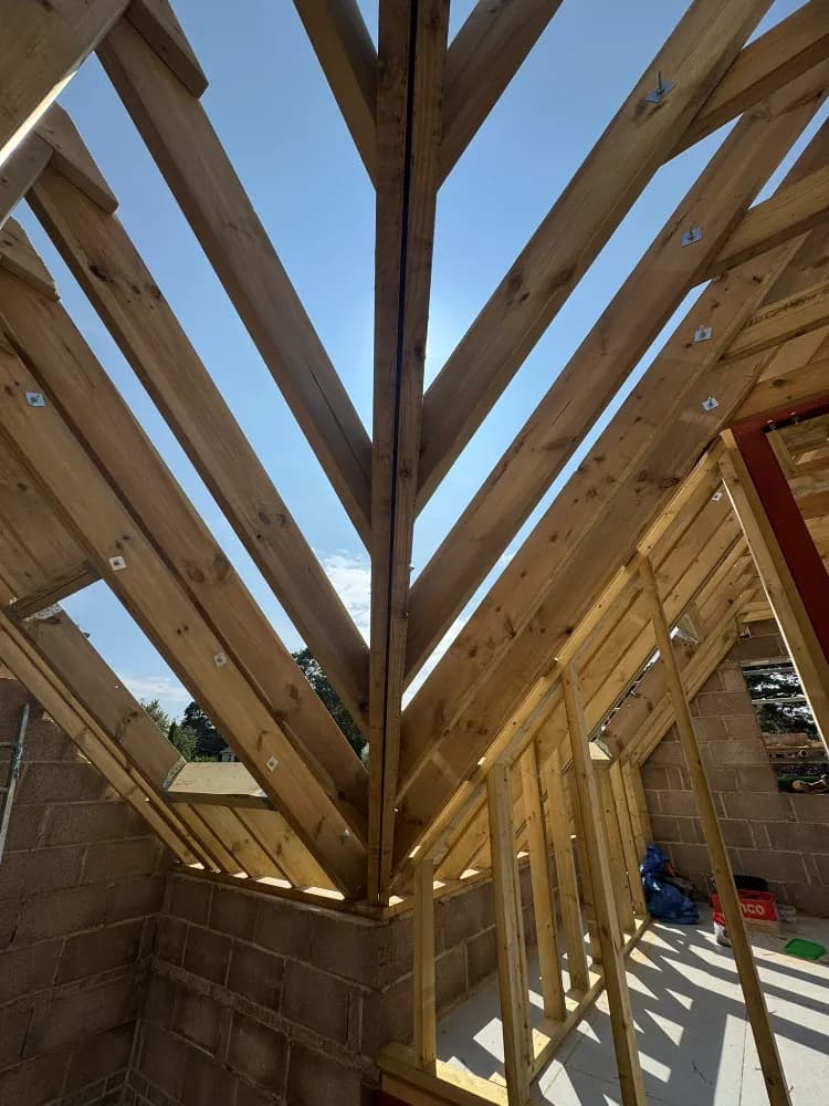 Hip roof timber rafters meeting at the ridge above new blockwork walls mid-build