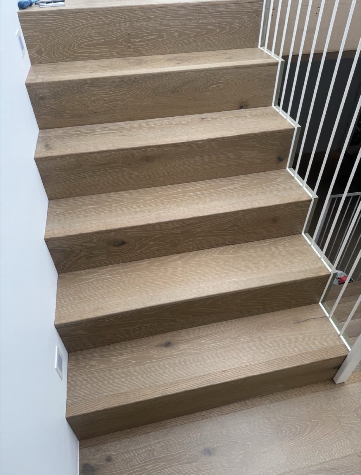 Renovated oak staircase with white metal spindle balustrade leading to matching wood flooring