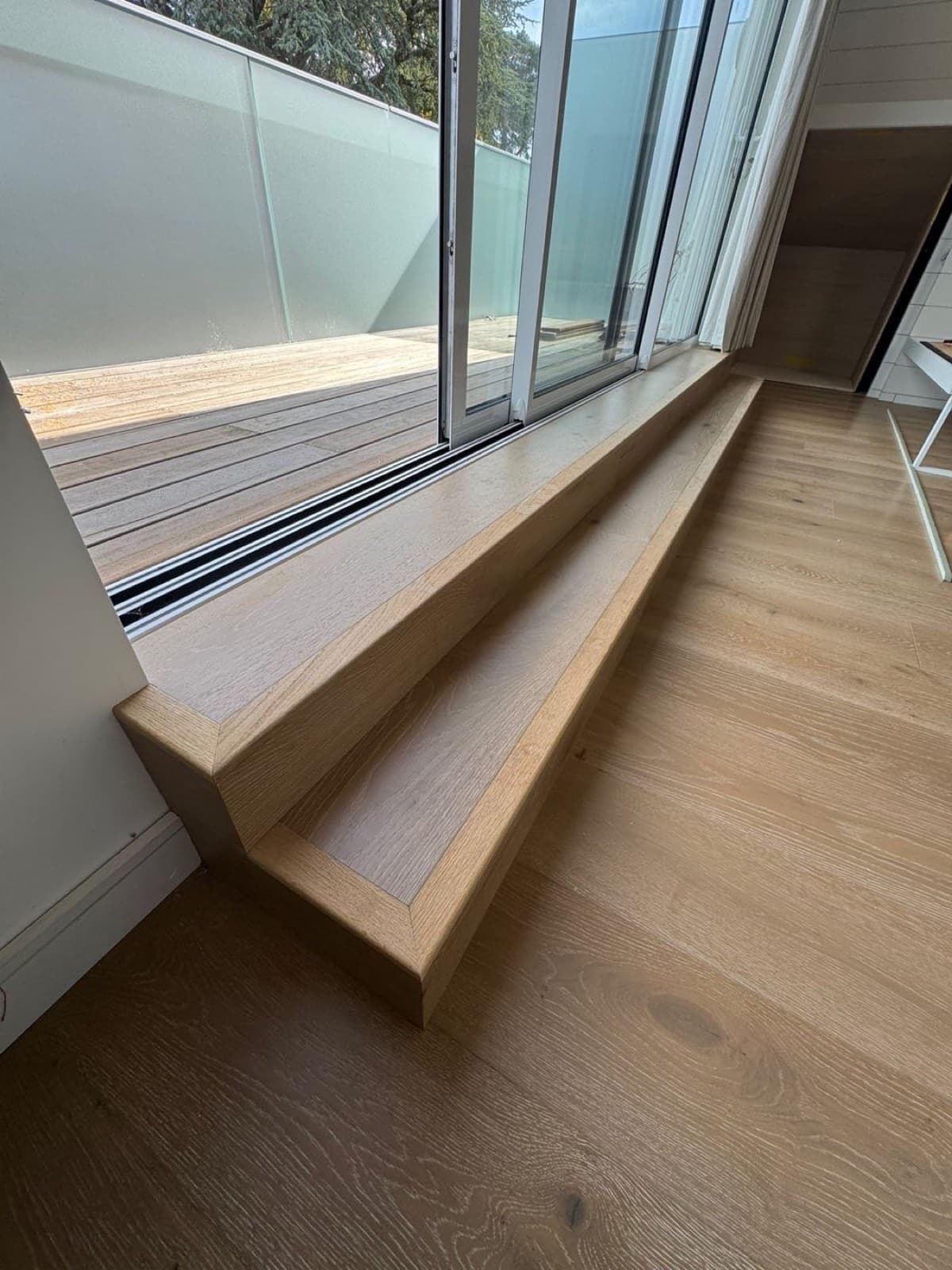 Wide-plank engineered oak flooring fitted in a plastered extension with patio doors