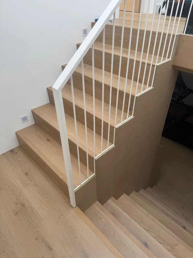 Finished staircase with white spindle balustrade and oak-effect treads matching the floor
