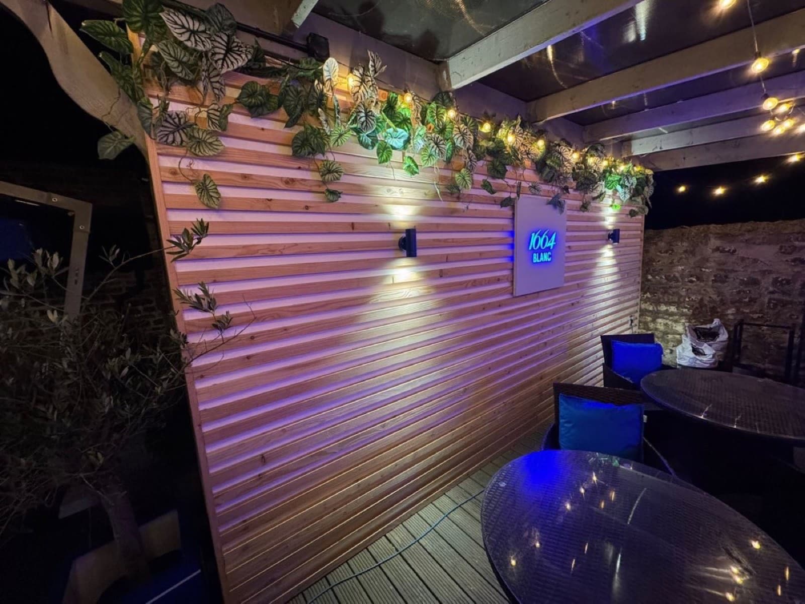 Horizontal timber cladding wall with lighting in an outdoor bar seating area at night
