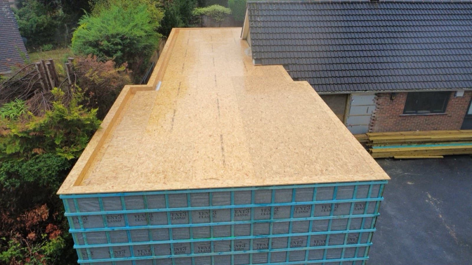 Aerial view of a timber-frame house extension roof deck under construction