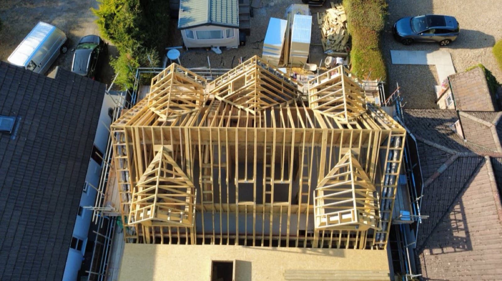 Aerial view of a timber frame roof and dormers under construction on a house extension