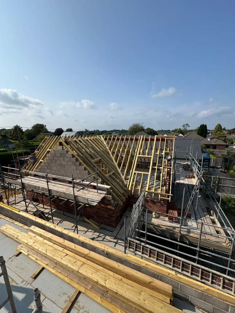 Hip roof timber rafters meeting at the ridge above new blockwork walls mid-build